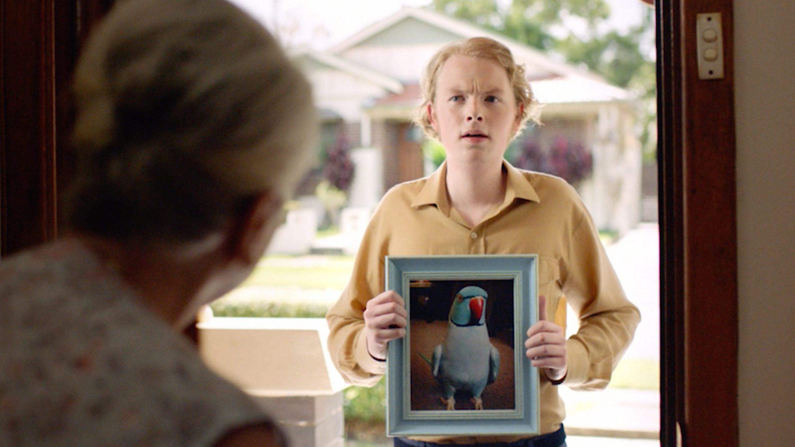 Man at door holding photo of a parrot